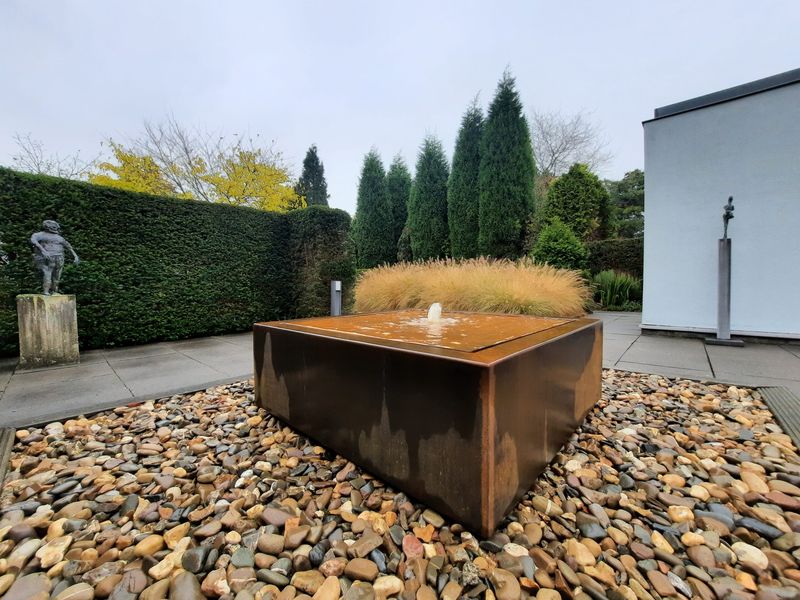 Table d'eau Taula en acier corten dans un jardin de gravier