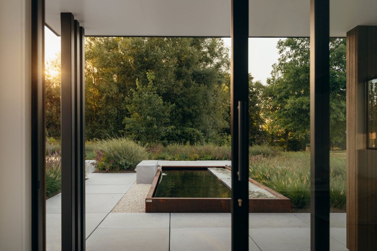 Bassin allonge en acier corten sur mesure, vu depuis le pavillon de jardin du jardin Outspiration d'Ebema