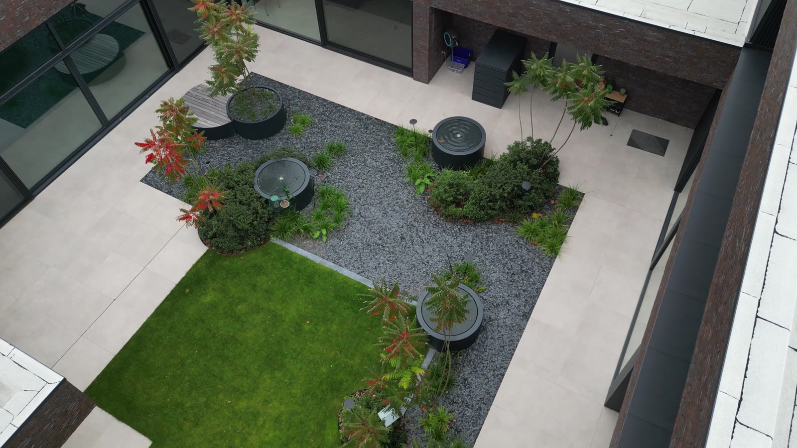Bovenaanzicht van de tuin met ronde watertafels en borders
