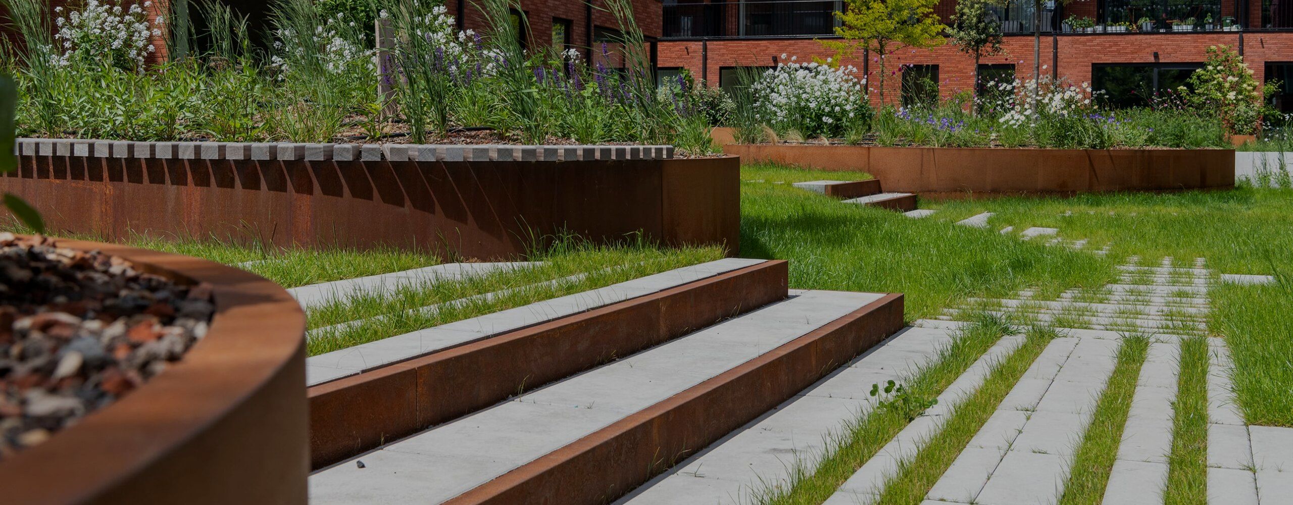 Bacs à plantes, murs de soutènement et marches en acier corten dans le jardin d'une résidence