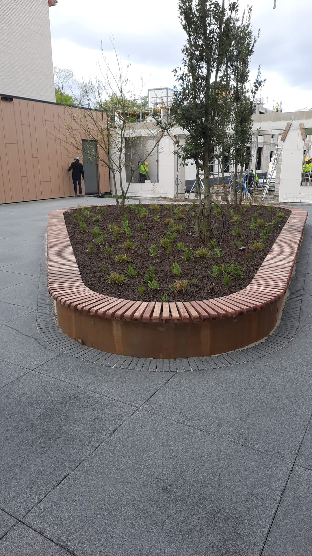 Organische cortenstalen plantenbak met houten zitbank bij een woonzorgcentrum in Rumst