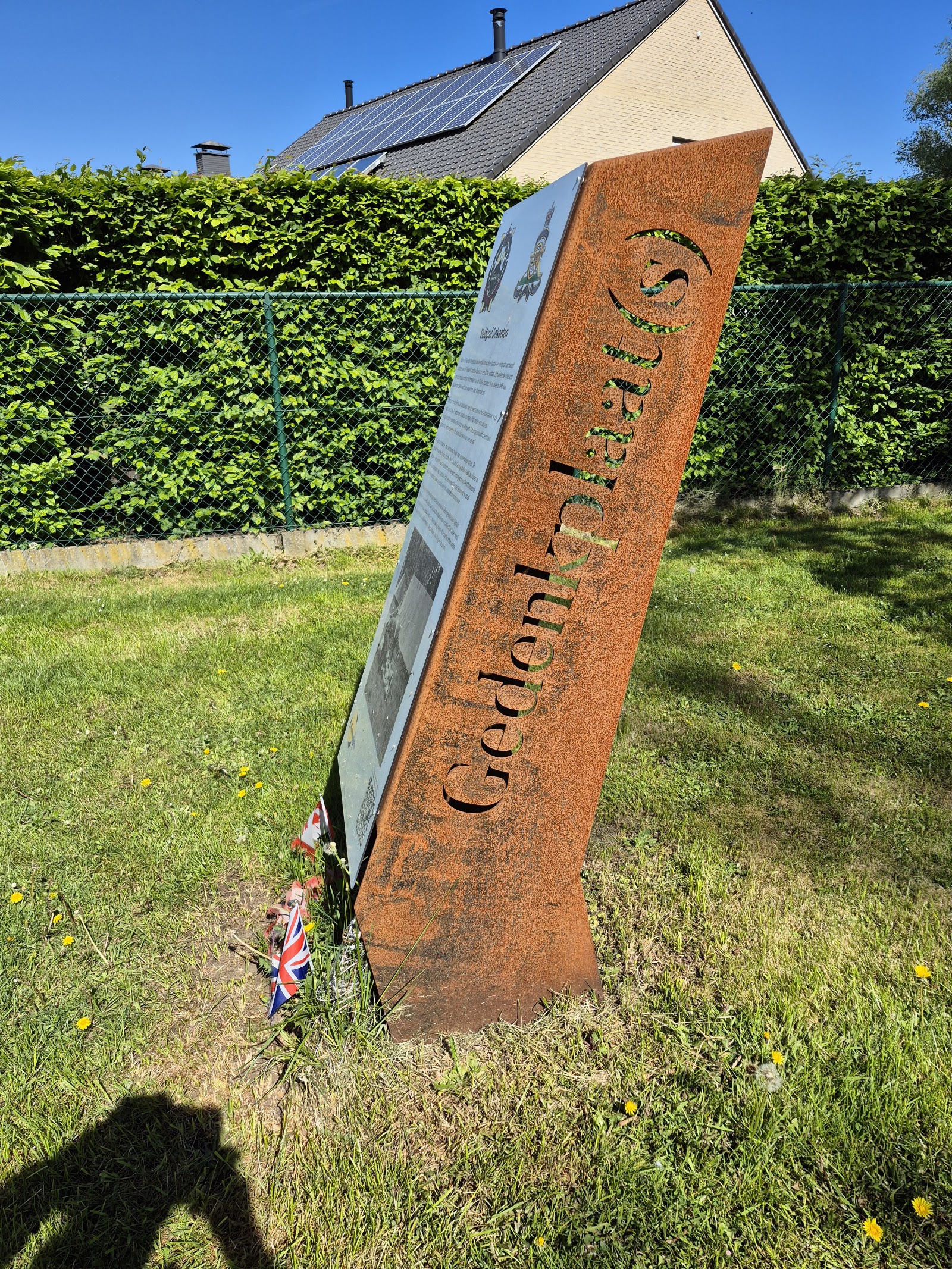 Zijaanzicht van de cortenstalen gedenkzuil met uitgesneden letters