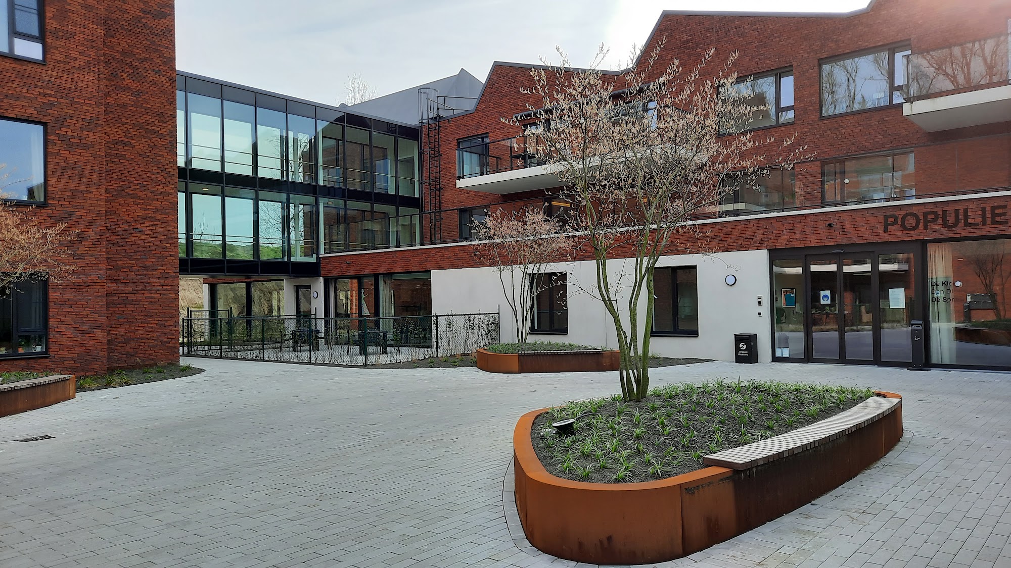 Plein met cortenstalen plantenbak en boom bij woonzorgcentrum Populierenhof