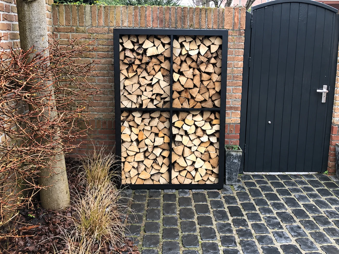 Zwarte houtopslag met 4 vakken tegen een bakstenen muur