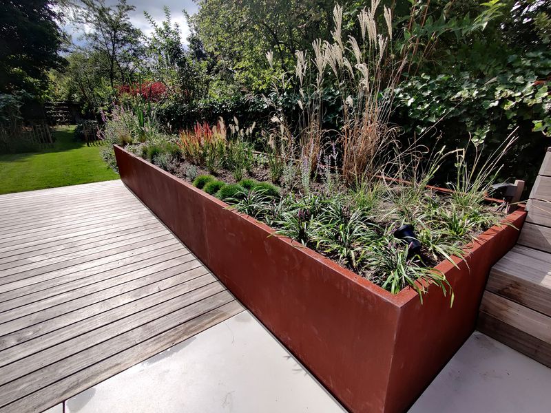 Bac à plantes en acier corten avec graminées sur une terrasse