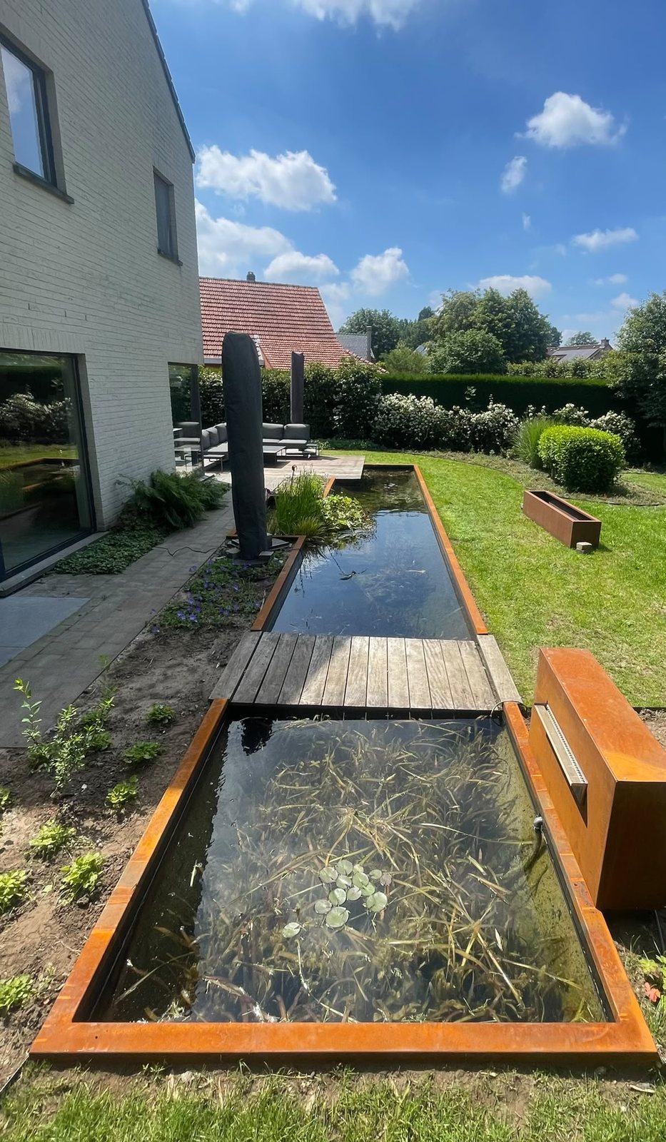 Houten vlonder over de vijver met cortenstalen vijverrand
