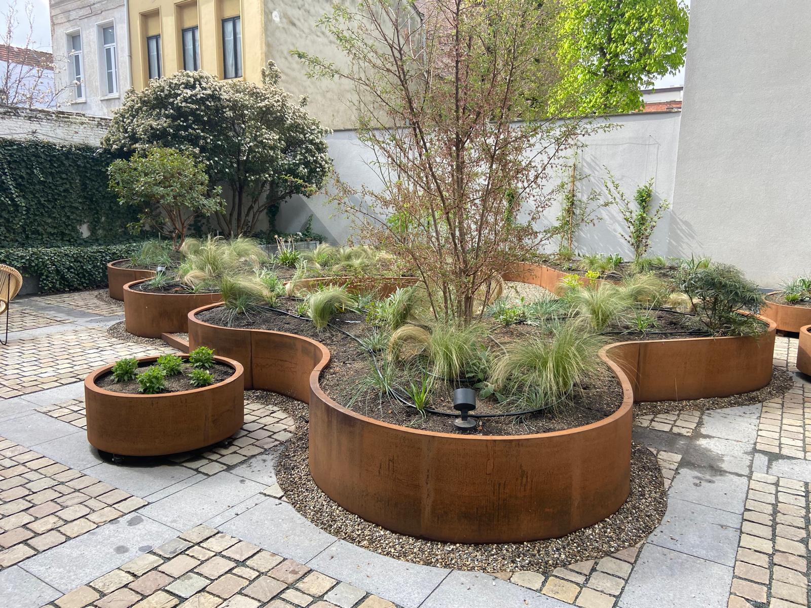 Golvende Geroba plantenbakken rond een boom in de kantoortuin van Ackermans & Van Haaren